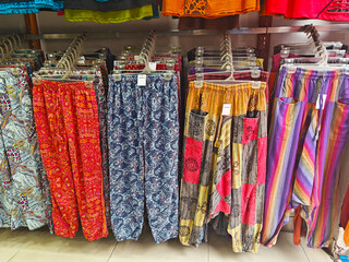 Colorful patterned pants displayed on hangers in a retail store, showcasing vibrant designs and textures