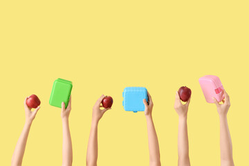 Female hands with school lunch boxes and red apples on yellow background