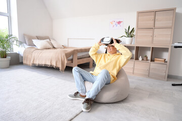 Naklejka premium Teenage boy using VR glasses in bedroom