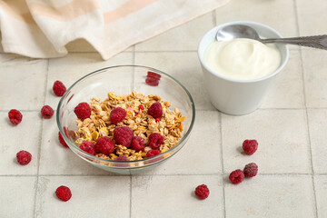Bowls of tasty granola with yogurt on light tile table