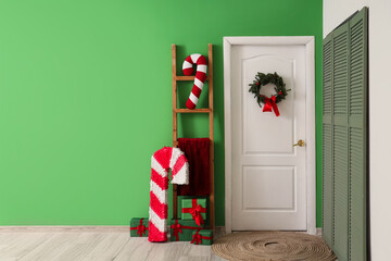 Interior of hall with Christmas wreath on white door, ladder and folding screen