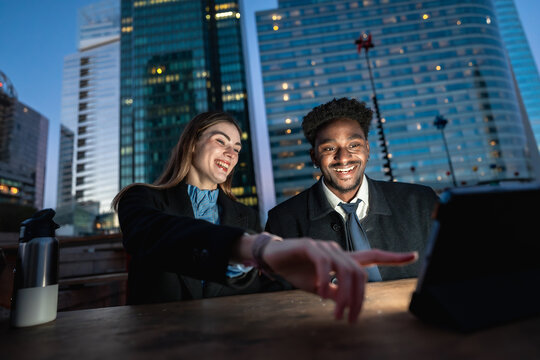 Diverse colleagues laughing watching digital tablet in city - Powered by Adobe