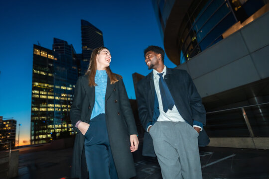 Diverse business colleagues walking and talking at night - Powered by Adobe