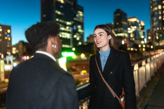 Business colleagues discussing work on city bridge at night