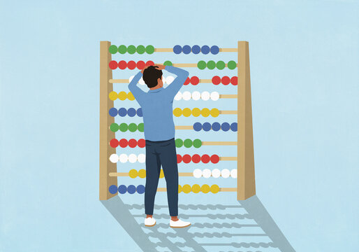 Confused man with head in hands looking at large abacus
