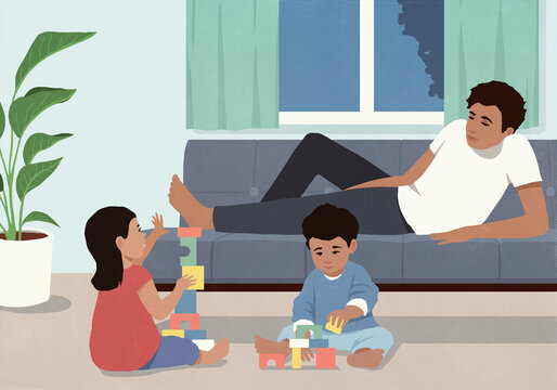 Father laying on sofa, relaxing and watching kids playing with toy blocks at home

