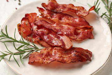Plate with fried bacon rashers and rosemary on white background, closeup