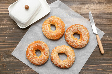 Baking paper of tasty bagels with sesame seeds on wooden background