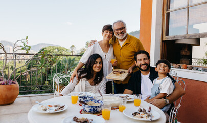 Family enjoying a joyful Brazilian churrasco meal on a sunny balcony