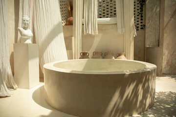 An elegant spa area featuring a round stone tub and gentle textiles