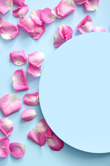 Blank card with beautiful pink rose petals on blue background