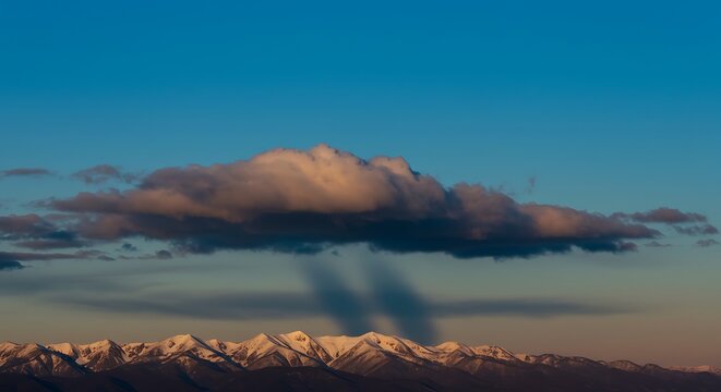 Majestic Snow-capped Mountain Range Under Dramatic Cloudy Sky During Sunset - Powered by Adobe