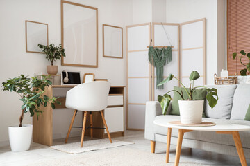 Workplace with laptop and blank posters on white wall in room