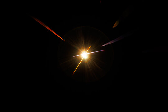 Lens Flare. Light over black background. Easy to add overlay or screen filter over photos. Abstract sun burst with digital lens flare background. Gleams rounded and hexagonal shapes, rainbow halo.