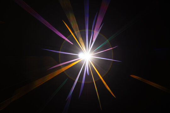 Lens Flare. Light over black background. Easy to add overlay or screen filter over photos. Abstract sun burst with digital lens flare background. Gleams rounded and hexagonal shapes, rainbow halo.
