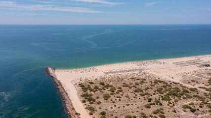 Scenic aerial view of sandy beach with umbrellas and clear blue water, showcasing vibrant summer atmosphere and natural beauty. Tavira Portugal Algarve