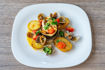 Delicious seafood dish featuring tender fish fillet, roasted potatoes, and fresh vegetables, beautifully arranged on a white plate for culinary presentation