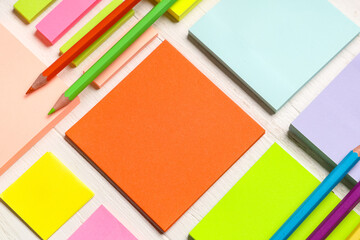 Different blank sticky notes and pencils on white wooden background, closeup