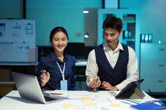 Financial analysts work overtime analyzing data on tablets, laptops, and graphs. Collaboration, teamwork, and planning.