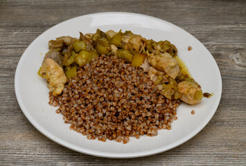 Focus on the dish's juiciness and texture. Buckwheat grains, pieces of meat, and vegetables are visible against the countertop, adding life context and warmth to the shot.