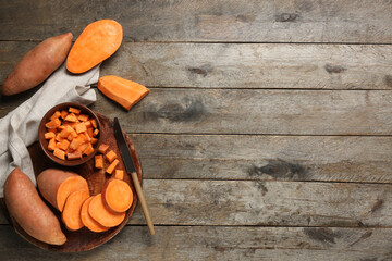 Composition with tray, knife and fresh sweet potatoes on wooden background