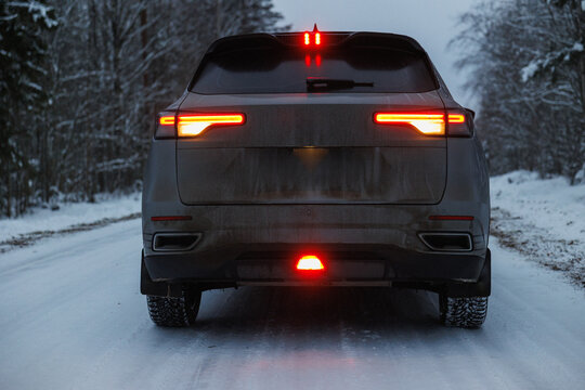 Centered SUV Rear Lights On Snow, Symmetrical Brake Pattern Reflecting On Wet Surface, Dirty Hatchback