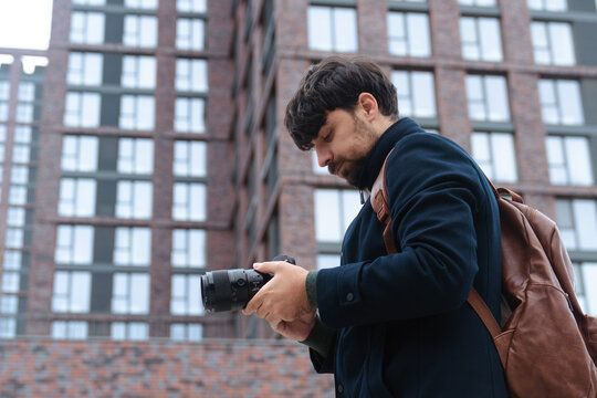 Man Inspecting Camera in Urban Setting