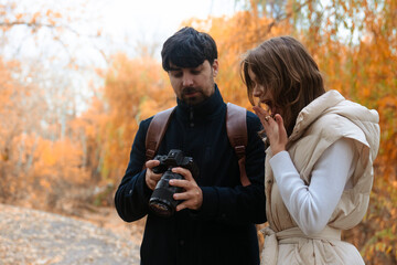 Couple Reviewing Camera Photos in Autumn Park