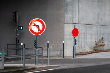 An intriguing view of a stark urban intersection highlighted by contrasting traffic signs against a gray concrete backdrop, evoking themes of navigation and regulation.