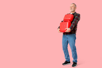 Mature man with canisters on pink background