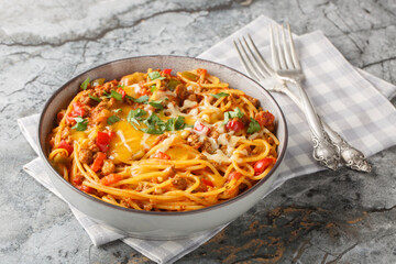 One pot Taco Pasta with ground beef, green chili, onion, cheese, tomatoes, spices close-up in a plate on the table. Horizontal closeup on the plate on the table. Horizontal