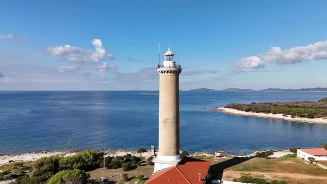 Rotating drone aerial around lighthouse tower of the Veli Rat on Dugi Otok, Croatia.Coastline with turquoise Adriatic Sea, and bright sunny weather in Zadar county.