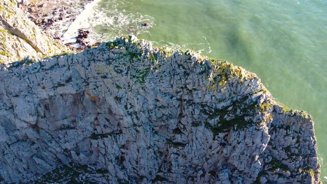 Dramatic Rising Pan Down of Strange Rock Formation on British Coastline. Travel Nature Drone Clip. Beautiful Welsh Gower Peninsula Coast.