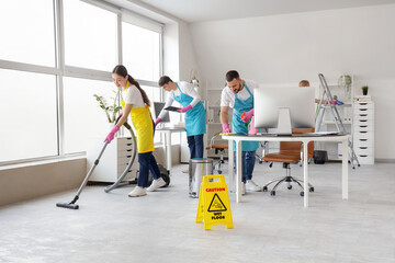 Team of young janitors cleaning in office