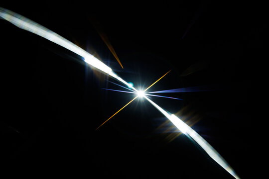 Lens Flare. Light over black background. Easy to add overlay or screen filter over photos. Abstract sun burst with digital lens flare background. Gleams rounded and hexagonal shapes.