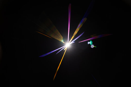 Lens Flare. Light over black background. Easy to add overlay or screen filter over photos. Abstract sun burst with digital lens flare background. Gleams rounded and hexagonal shapes.