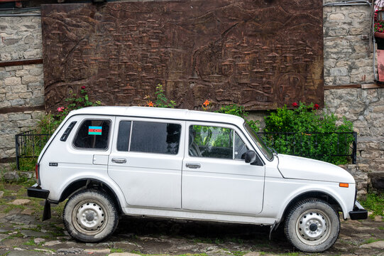 LAHIJ, AZERBAIJAN - JUNE 17, 2025: White Lada car parked beside an illustrated town map in Lahij, Azerbaijan.