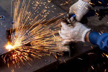 Worker Using Cutting Torch to Cut Metal With Bright Flying Sparks in Industrial Workshop