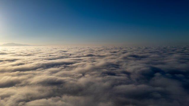 Aerial view of a serene, fluffy cloudscape stretching to the horizon, kissed by the sun's gentle glow, Montecito, California, United States.