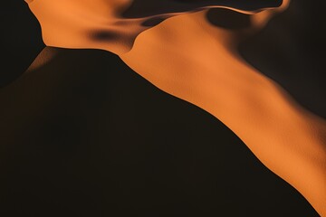 An artistic view of sand dunes showcasing flowing shapes and warm orange tones contrasted against darker shadows.