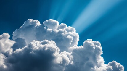 Majestic cumulus cloud formation casting powerful crepuscular sun rays against a vibrant blue sky background.