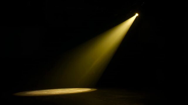 Lighting cue starting angled yellow spotlight casting beam across dark stage, forming round spot