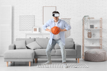 Sporty young man in VR glasses playing with ball at home