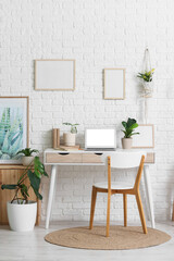 Interior of office with workplace, blank frames and houseplants