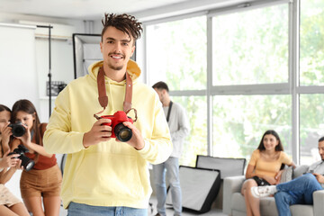 Smiling male photographer with camera during courses in studio