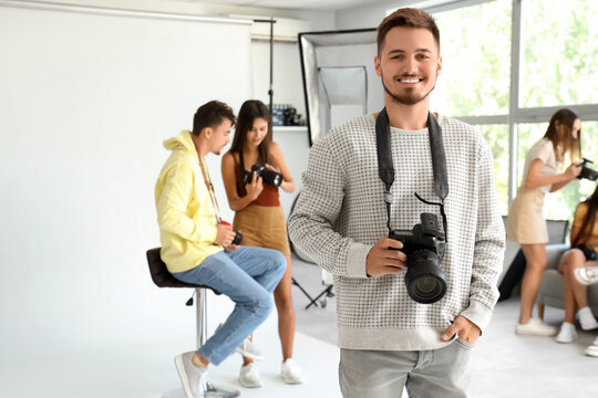 Smiling male photographer with camera during courses in studio - Powered by Adobe