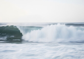 Ocean wave breaking on a calm day. Abstract nature background for travel and environmental concept. Sea foam and motion blur with a simple sky.