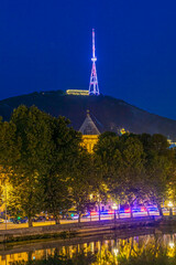 Night view of Zion Cathedral of the Dormition of Tbilisi, funicular and TV tower. Warm light and traces of car headlights. Dark blue sky
