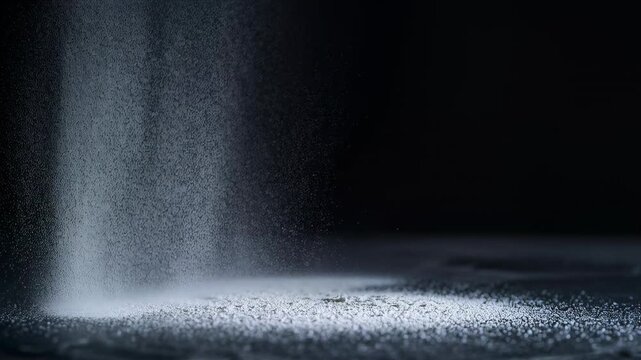 Releasing top feed spotlit, forming falling jet of white granules on stage, making ring