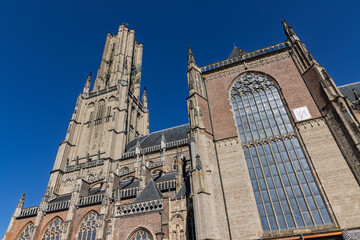 Low angle view of the side facade of Eusebius Church in Arnhem, showing large stained glass windows and Gothic brick architecture.